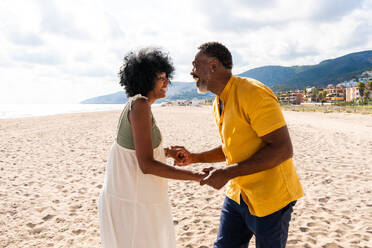 Beautiful mature black couple of lovers dating at the seaside - Married african middle-aged couple bonding and having fun outdoors, concepts about relationship, lifestyle and quality of life - DMDF10402