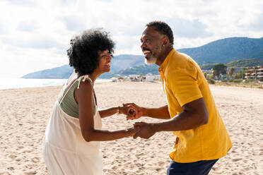 Beautiful mature black couple of lovers dating at the seaside - Married african middle-aged couple bonding and having fun outdoors, concepts about relationship, lifestyle and quality of life - DMDF10403