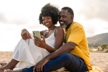 Beautiful mature black couple of lovers dating at the seaside - Married african middle-aged couple bonding and having fun outdoors, concepts about relationship, lifestyle and quality of life - DMDF10452