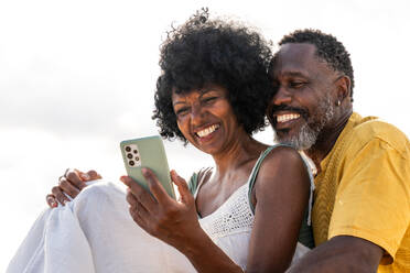 Beautiful mature black couple of lovers dating at the seaside - Married african middle-aged couple bonding and having fun outdoors, concepts about relationship, lifestyle and quality of life - DMDF10454