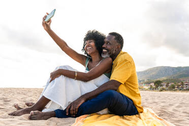 Beautiful mature black couple of lovers dating at the seaside - Married african middle-aged couple bonding and having fun outdoors, concepts about relationship, lifestyle and quality of life - DMDF10455