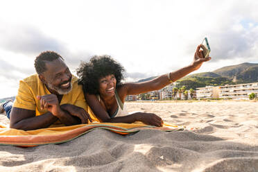 Beautiful mature black couple of lovers dating at the seaside - Married african middle-aged couple bonding and having fun outdoors, concepts about relationship, lifestyle and quality of life - DMDF10463