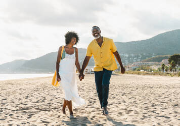 Beautiful mature black couple of lovers dating at the seaside - Married african middle-aged couple bonding and having fun outdoors, concepts about relationship, lifestyle and quality of life - DMDF10477