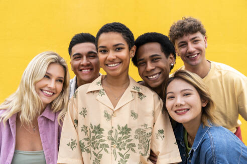 Portrait of laughing multi-ethnic friends against yellow wall - OIPF03929