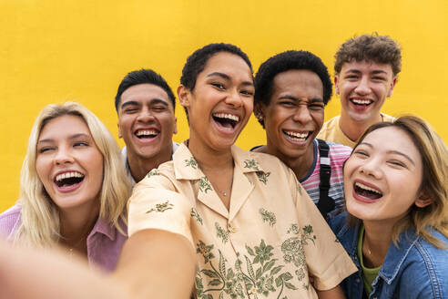 Portrait of laughing multi-ethnic friends against yellow wall - OIPF03930
