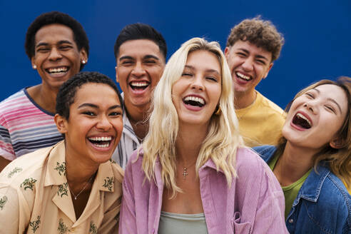 Portrait of laughing multi-ethnic friends against yellow wall - OIPF03942