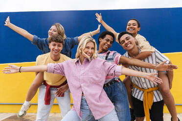 Gruppe junger Freunde mit farbenfroher Kleidung, die fröhlich vor einer Wand posieren - OIPF04001
