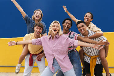 Gruppe junger Freunde mit farbenfroher Kleidung, die fröhlich vor einer Wand posieren - OIPF04002