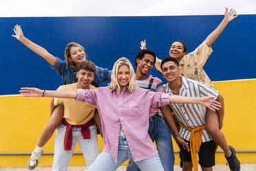 Gruppe junger Freunde mit farbenfroher Kleidung, die fröhlich vor einer Wand posieren - OIPF04004