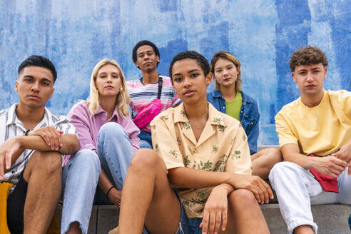 Confident young people sitting on steps in front of wall - OIPF04015
