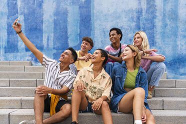 Fröhliche Gruppe junger Leute, die ein Selfie auf einer Treppe vor einer Mauer machen - OIPF04024