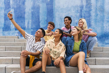 Happy group of young people taking selfie on steps in front of wall - OIPF04024