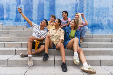 Happy group of young people taking selfie on steps in front of wall - OIPF04025