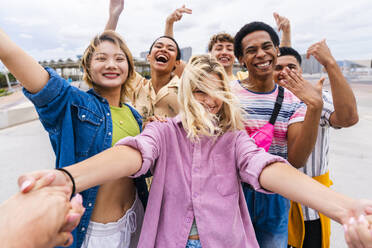 Glückliche junge Freunde, die sich an den Händen halten und Spaß miteinander haben - OIPF04031