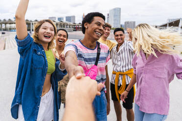 Glückliche junge Freunde, die sich an den Händen halten und Spaß miteinander haben - OIPF04034