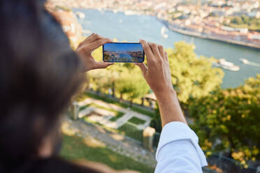 Mann fotografiert den Fluss Douro mit seinem Smartphone in der Stadt Porto in Portugal - BSZF02635