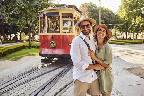 Glückliches Paar steht zusammen vor einer Straßenbahn - BSZF02637