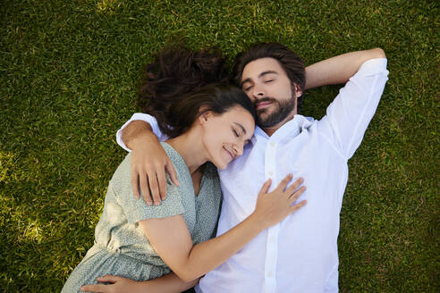 Loving young couple lying on grass - BSZF02641