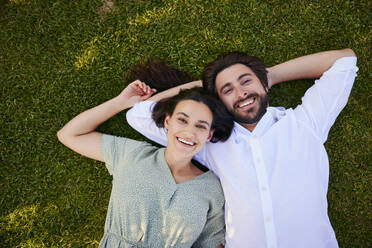 Happy young couple lying on grass - BSZF02642