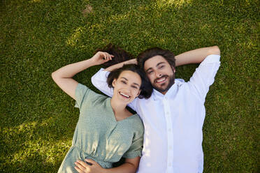 Happy couple lying together on grass - BSZF02644