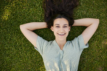 Smiling beautiful woman lying on grass - BSZF02645