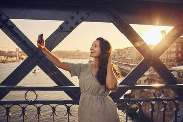 Glückliche Frau macht ein Selfie mit ihrem Smartphone auf der Dom-Luis-Brücke in Porto, Portugal - BSZF02648