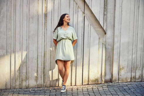 Smiling young woman leaning on wall - BSZF02652