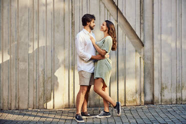 Loving young couple standing in front of wall - BSZF02653