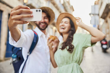 Happy young couple taking selfie through smart phone - BSZF02668