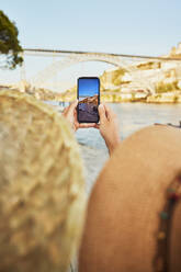 Mann und Frau fotografieren die Dom-Luis-Brücke mit ihrem Smartphone in Porto, Portugal - BSZF02677
