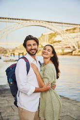 Glückliches Paar steht in der Nähe des Flusses Douro vor der Dom-Luis-Brücke in Porto, Portugal - BSZF02680