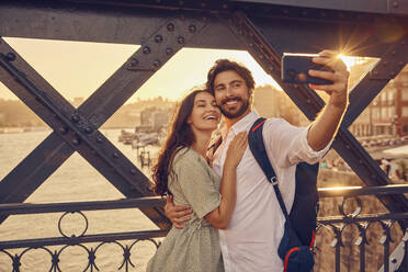 Glückliches Paar, das ein Selfie mit seinem Smartphone an der Dom-Luis-Brücke, Porto, Portugal, macht - BSZF02687