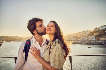 Glücklicher Mann küsst Frau vor dem Fluss Douro in Porto, Portugal - BSZF02699