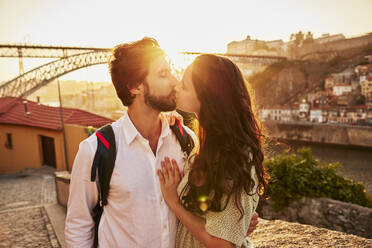 Young couple kissing in front of Dom Luis bridge, Porto, Portugal - BSZF02703