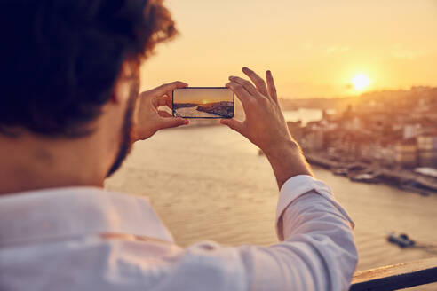 Mann fotografiert die Stadt Porto mit seinem Smartphone bei Sonnenuntergang in Portugal - BSZF02716