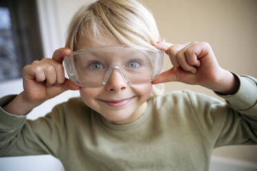 Playful boy wearing protective eyewear at new home - NJAF00812