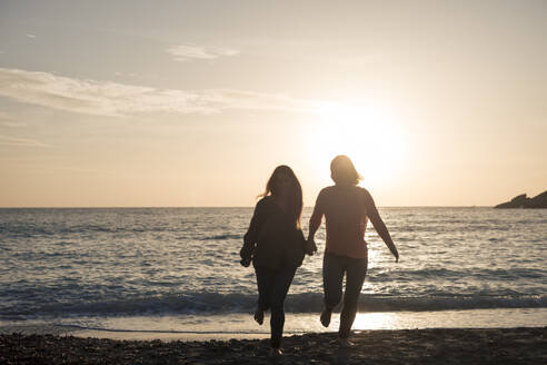 Unbekümmerte Freunde laufen am Strand bei Sonnenuntergang - JOSEF23664