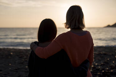 Freunde, die sich in den Armen liegen und ihre Freizeit am Strand verbringen - JOSEF23665