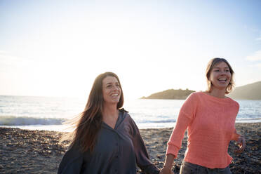 Happy friends spending leisure time together at sunset beach - JOSEF23709