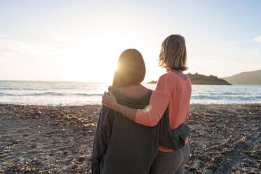 Friends with arms around spending leisure time together at sunset beach - JOSEF23711