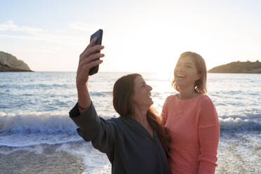 Cheerful friends taking selfie together on shore at beach - JOSEF23713