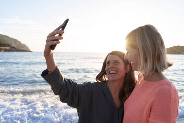 Glückliche Frau nimmt Selfie mit Freund am Strand am Ufer - JOSEF23714