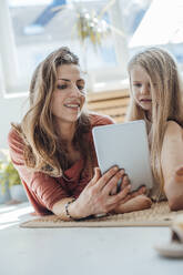 Lächelnde Mutter, die mit ihrer Tochter zu Hause einen Tablet-PC benutzt - JOSEF23750