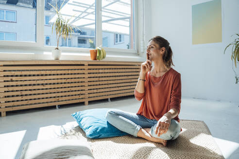 Frau sitzt mit Finger auf den Lippen zu Hause - JOSEF23766