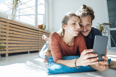 Happy couple taking selfie through smart phone at home - JOSEF23773