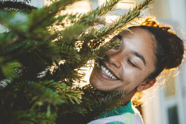 Happy young woman by Christmas tree - JOSEF23784