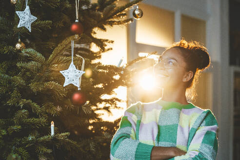 Junge Frau betrachtet den Weihnachtsbaum - JOSEF23796