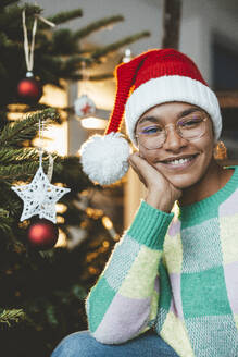 Lächelnde junge Frau mit Weihnachtsmannmütze an Weihnachten zu Hause - JOSEF23805