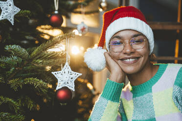 Lächelnde Frau mit Weihnachtsmannmütze an Weihnachten zu Hause - JOSEF23806