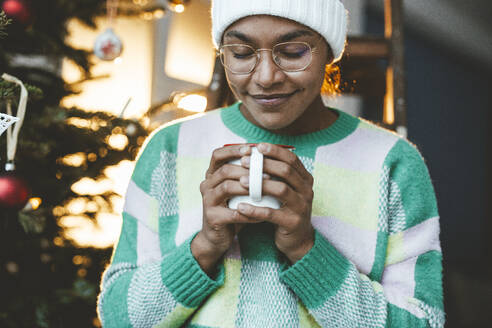 Lächelnde Frau mit Kaffeetasse im Stehen zu Hause - JOSEF23810